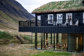 Yoga class seen through the window of a an exterior view of a lodge, with summer iceland landscape